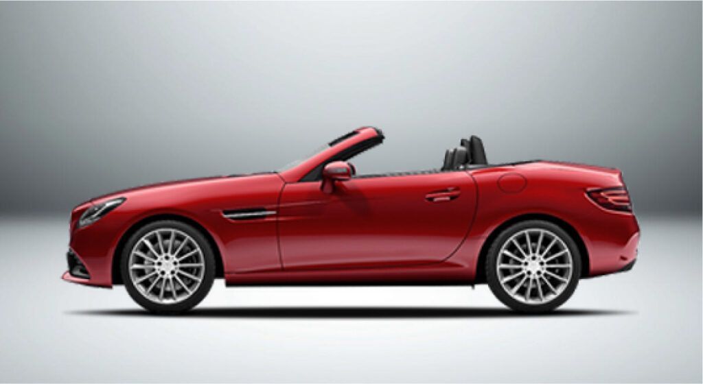Um carro esportivo conversível vermelho com a capota voltada para baixo sobre um fundo branco.