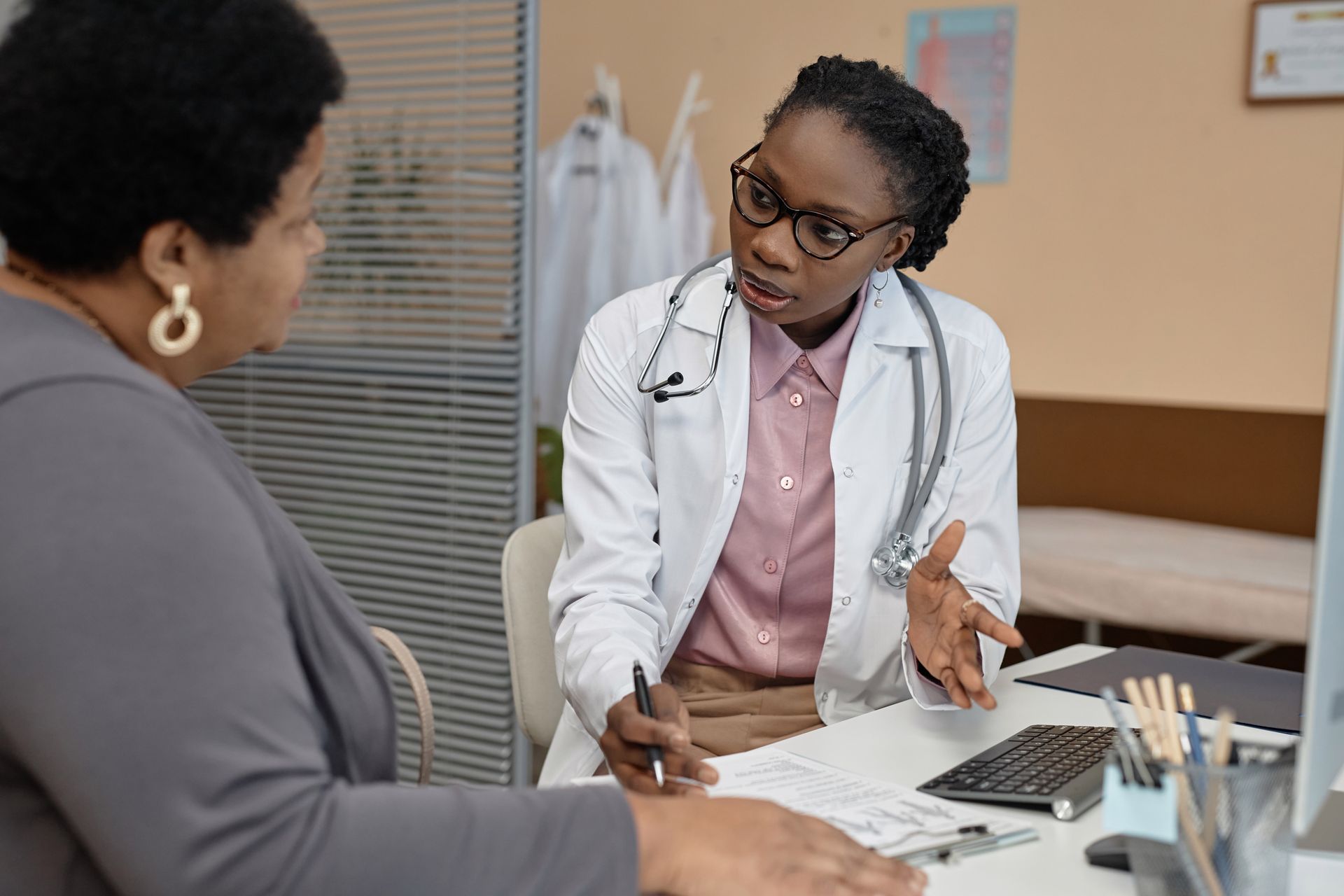Doctor in white coat discussing paperwork with a patient in a clinic office.