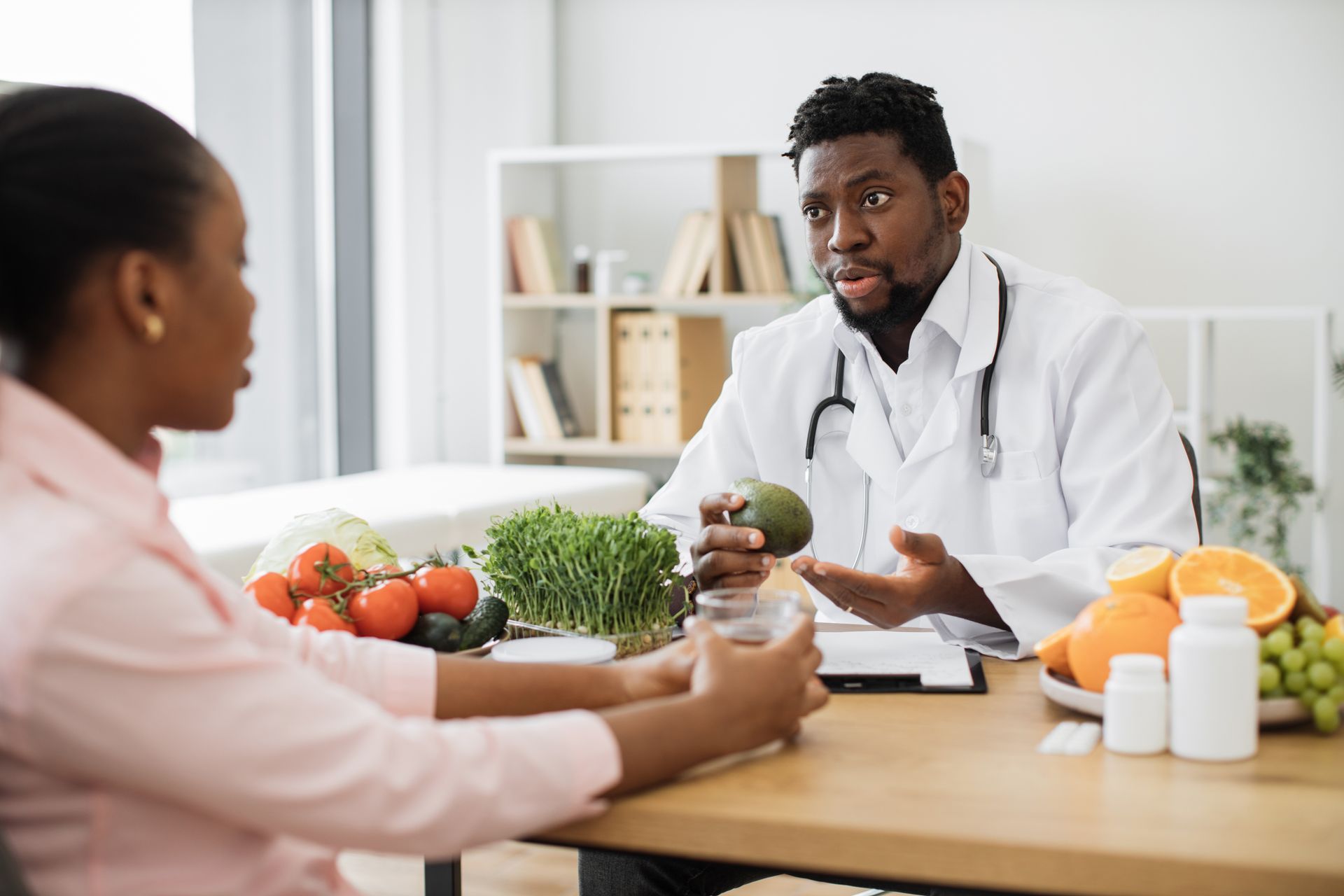 Doctor discussing healthy food choices with a patient at a table with fruits and vegetables