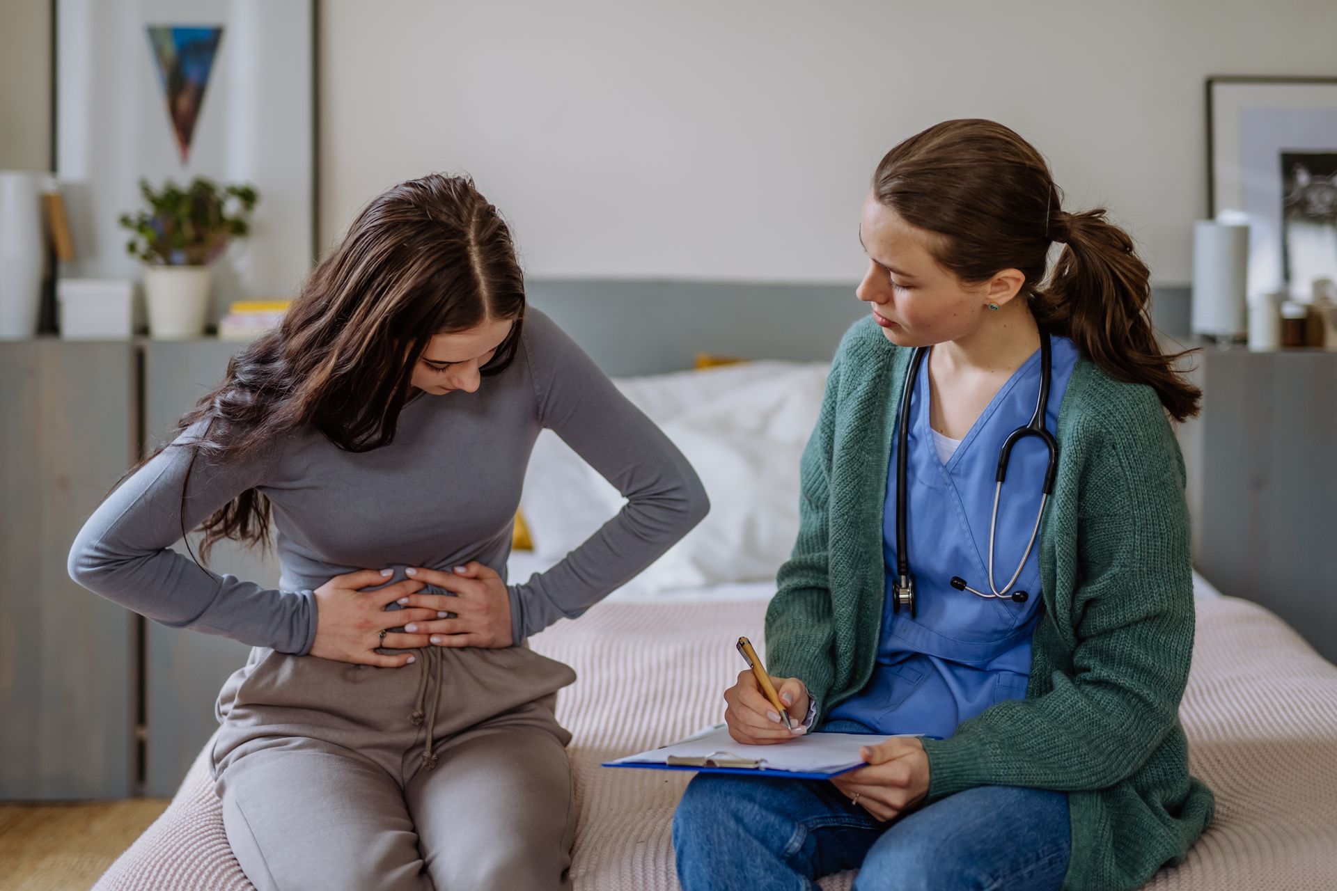 Patient holding stomach while speaking with doctor in a consultation room