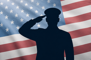 Silhouette of a soldier saluting in front of a waving American flag