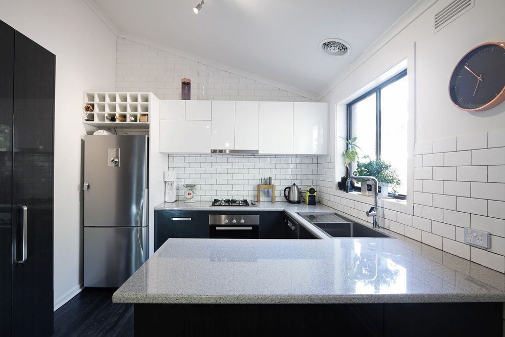 A Kitchen With Black And White Cabinets And A Clock On The Wall — Matt Walsh Plumbing in Jindera, NSW