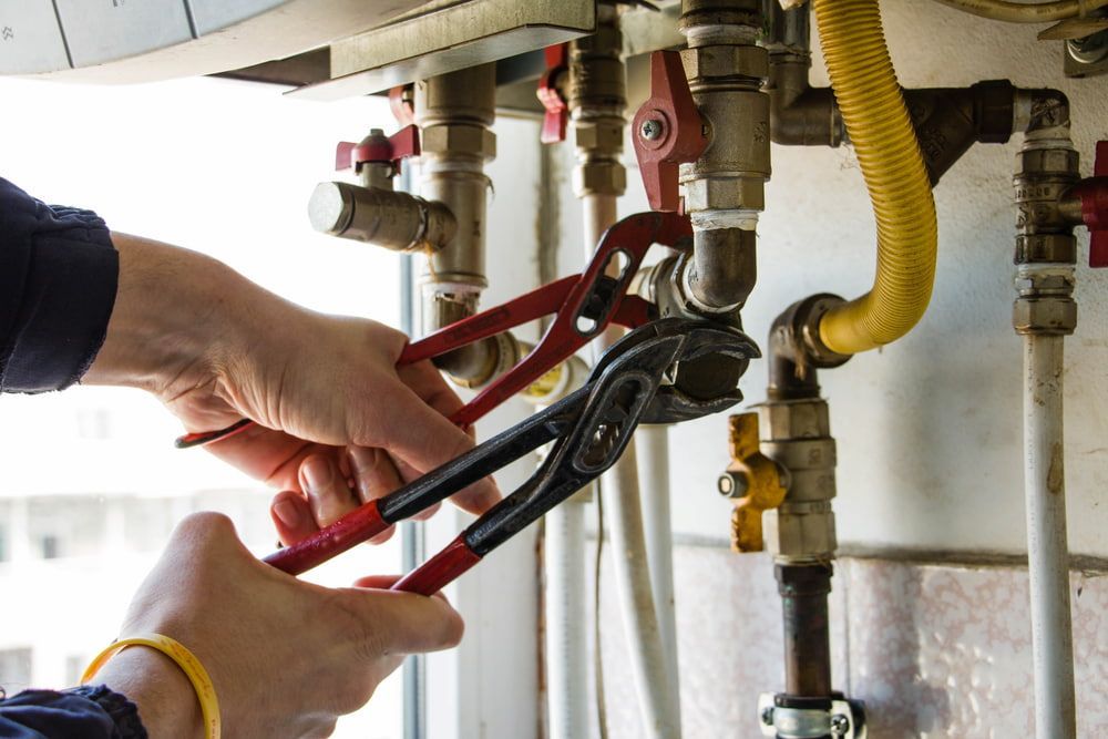A Person Is Fixing A Boiler With A Wrench — Matt Walsh Plumbing in Bandiana, VIC