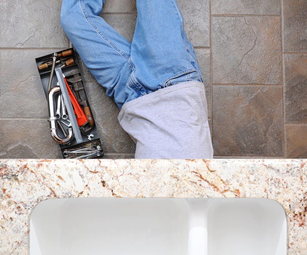 A Plumber Is Laying On The Floor Next To A Sink — Matt Walsh Plumbing in Lavington, NSW