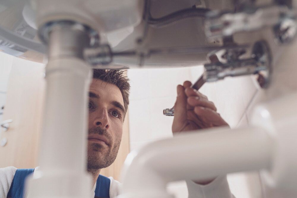 A Man Is Fixing A Sink With A Wrench — Matt Walsh Plumbing in Bandiana, VIC