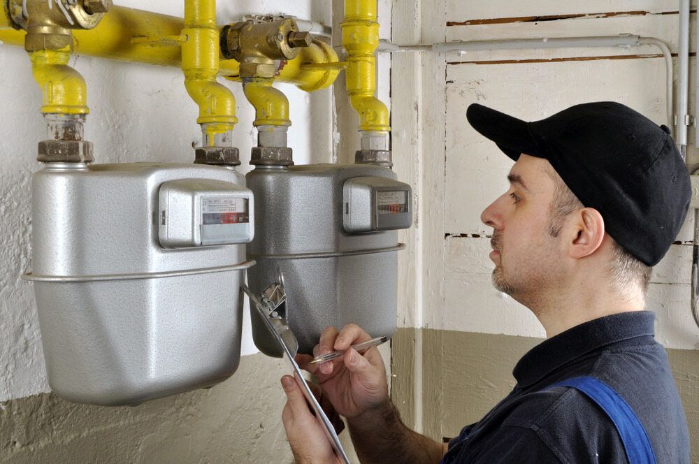 A Man Is Looking At Gas Meters — Matt Walsh Plumbing in Thurgoona, NSW