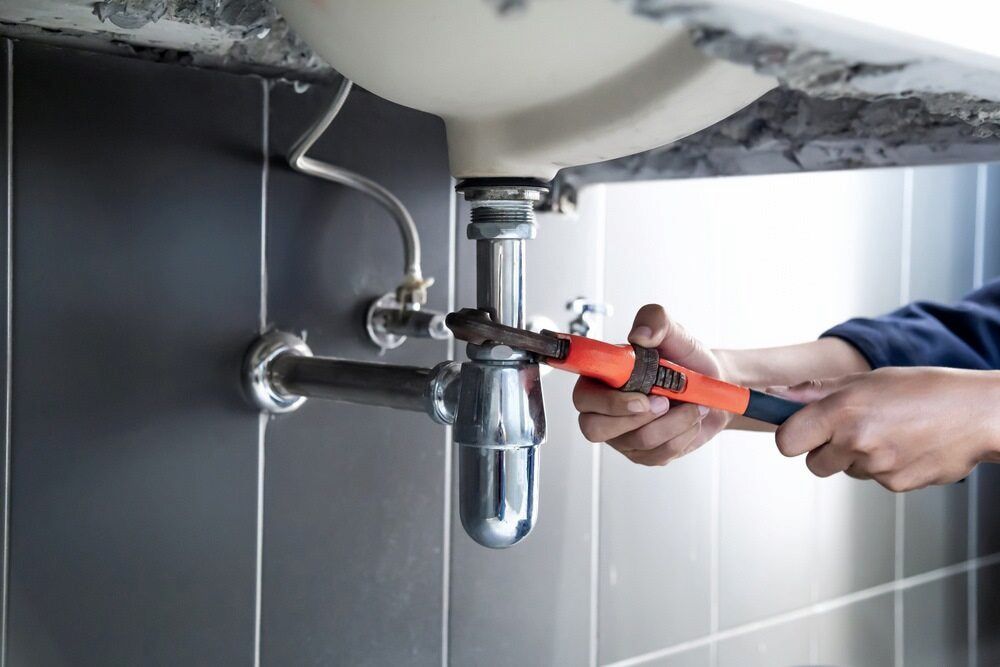 A Plumber Is Fixing A Sink Pipe With A Wrench — Matt Walsh Plumbing in Albury, NSW