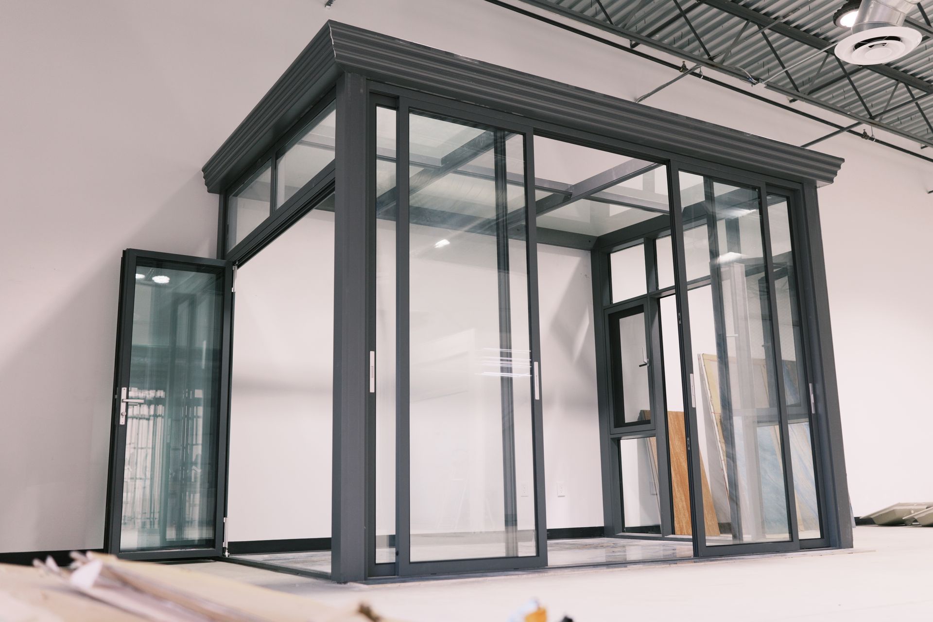 Modern glass office booth with gray metal frame in a bright indoor showroom