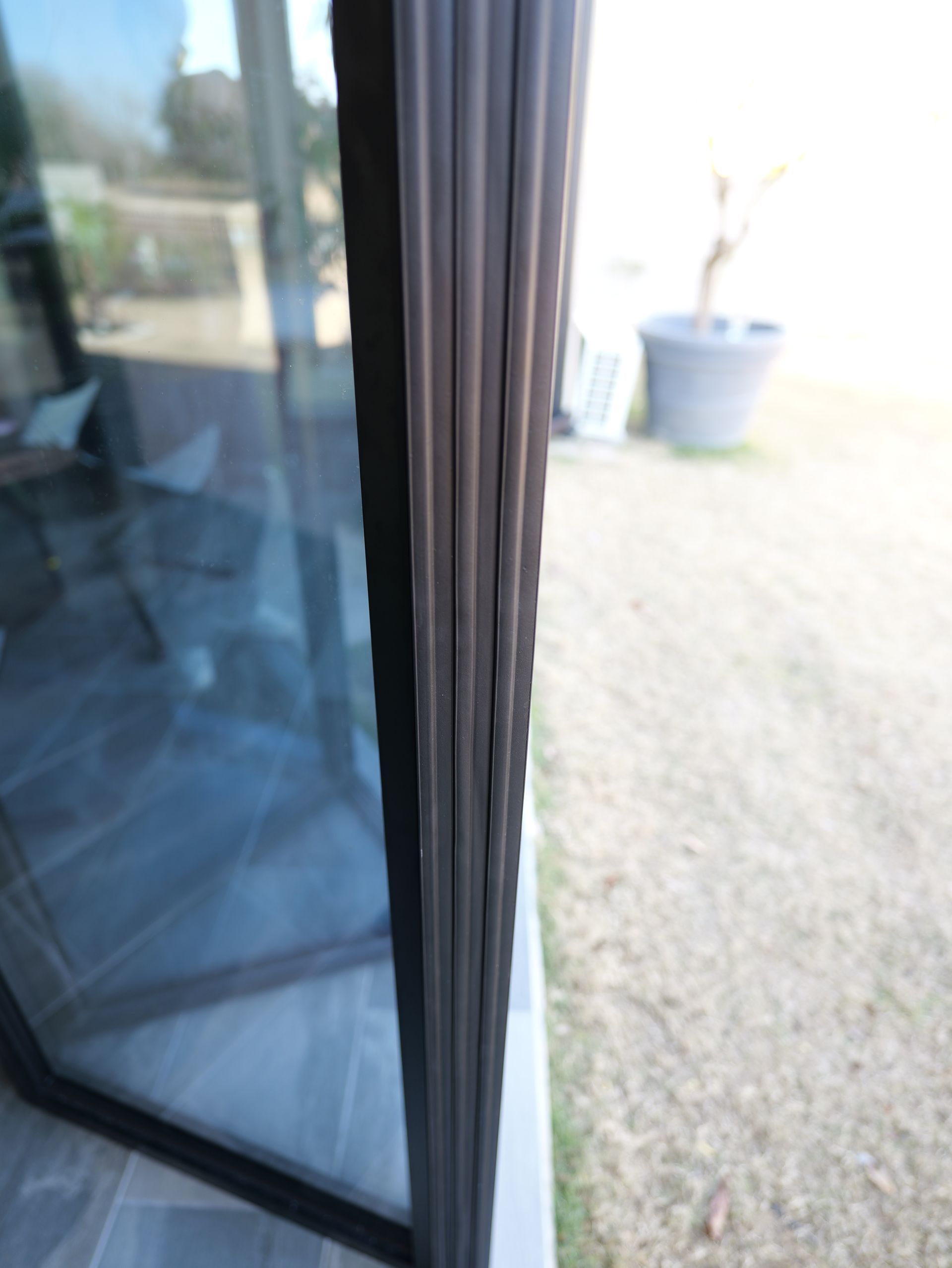 Sliding glass door opens to a sunlit patio with gravel and a large plant pot.