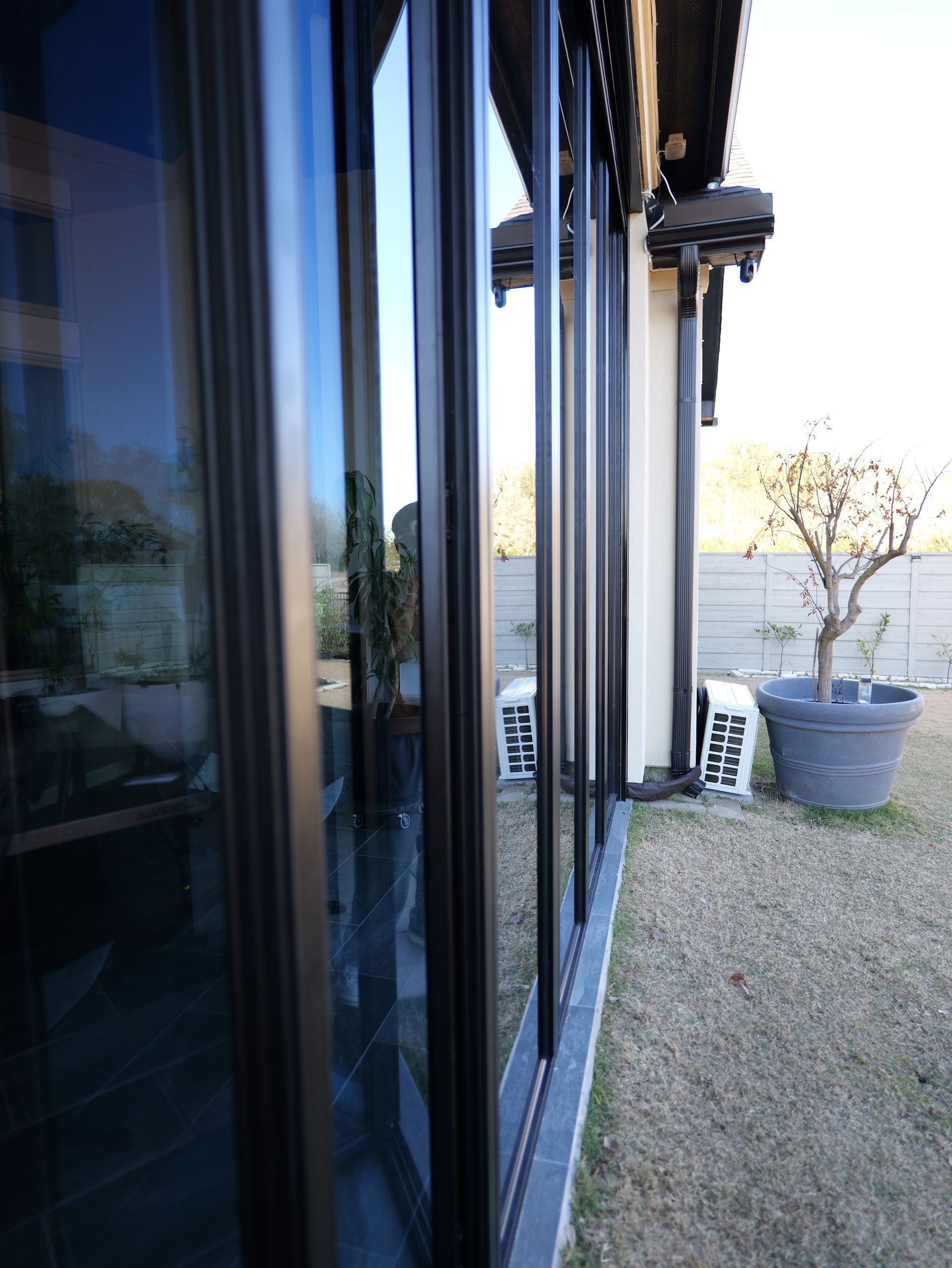 Sliding glass doors beside a gravel patio with a potted tree and a building in the distance