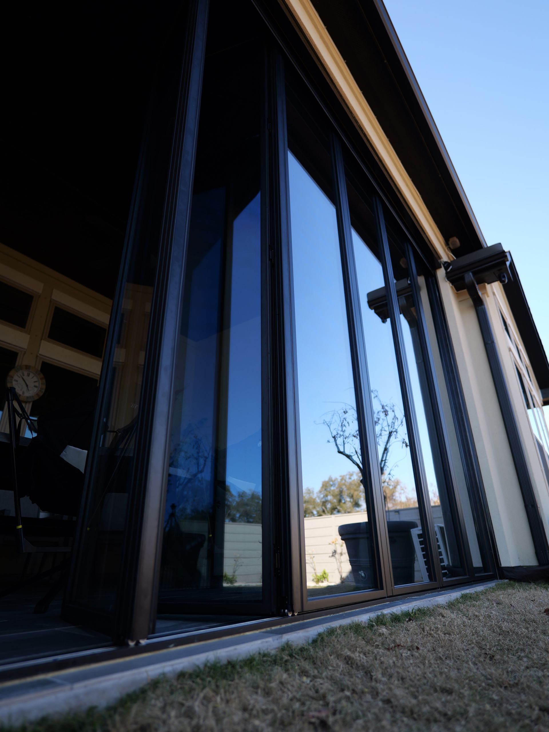Modern house with large reflective glass windows and a slanted roof viewed from a low angle
