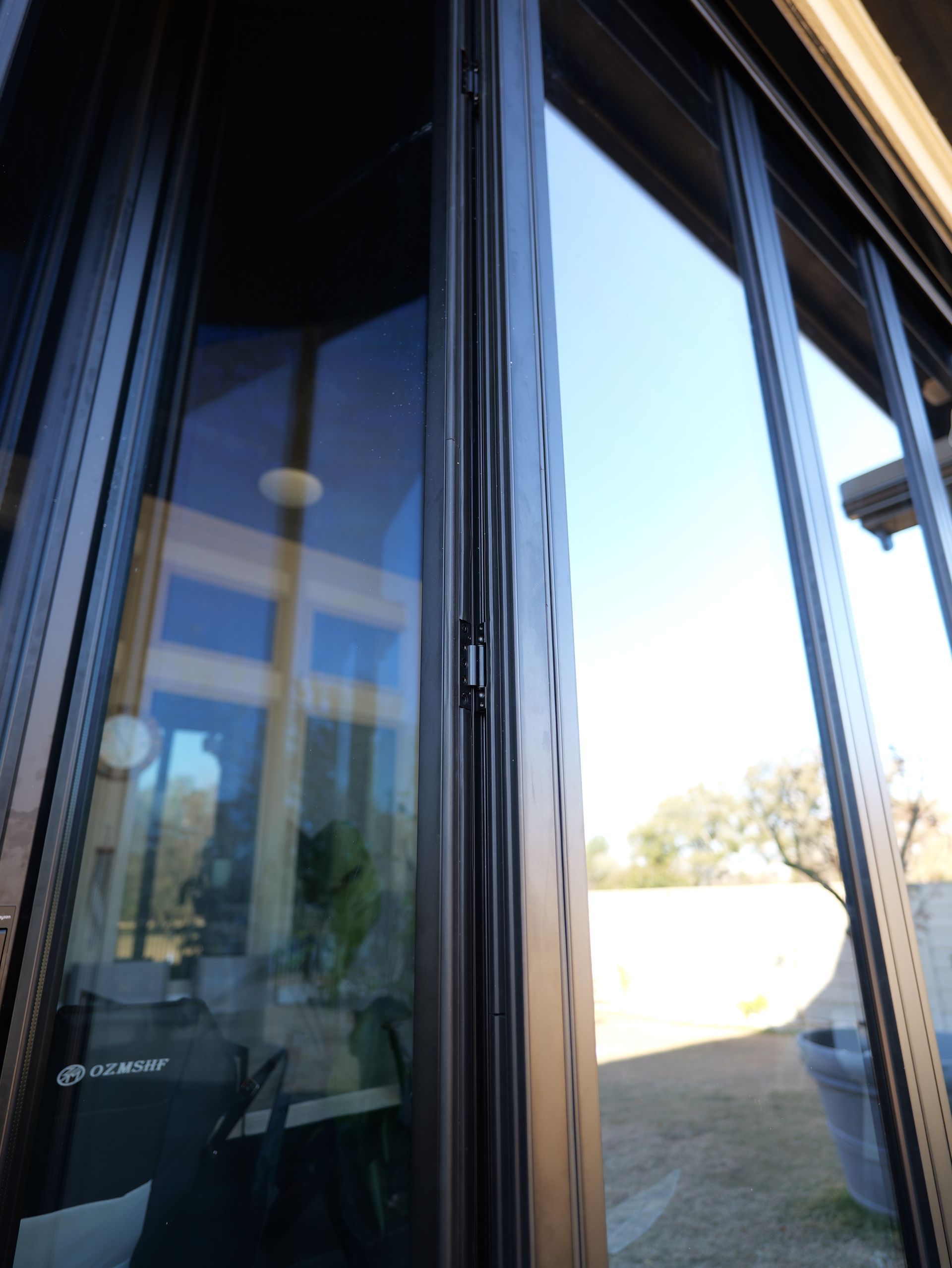 Glass doors opening to a bright outdoor patio with a blue sky and trees beyond