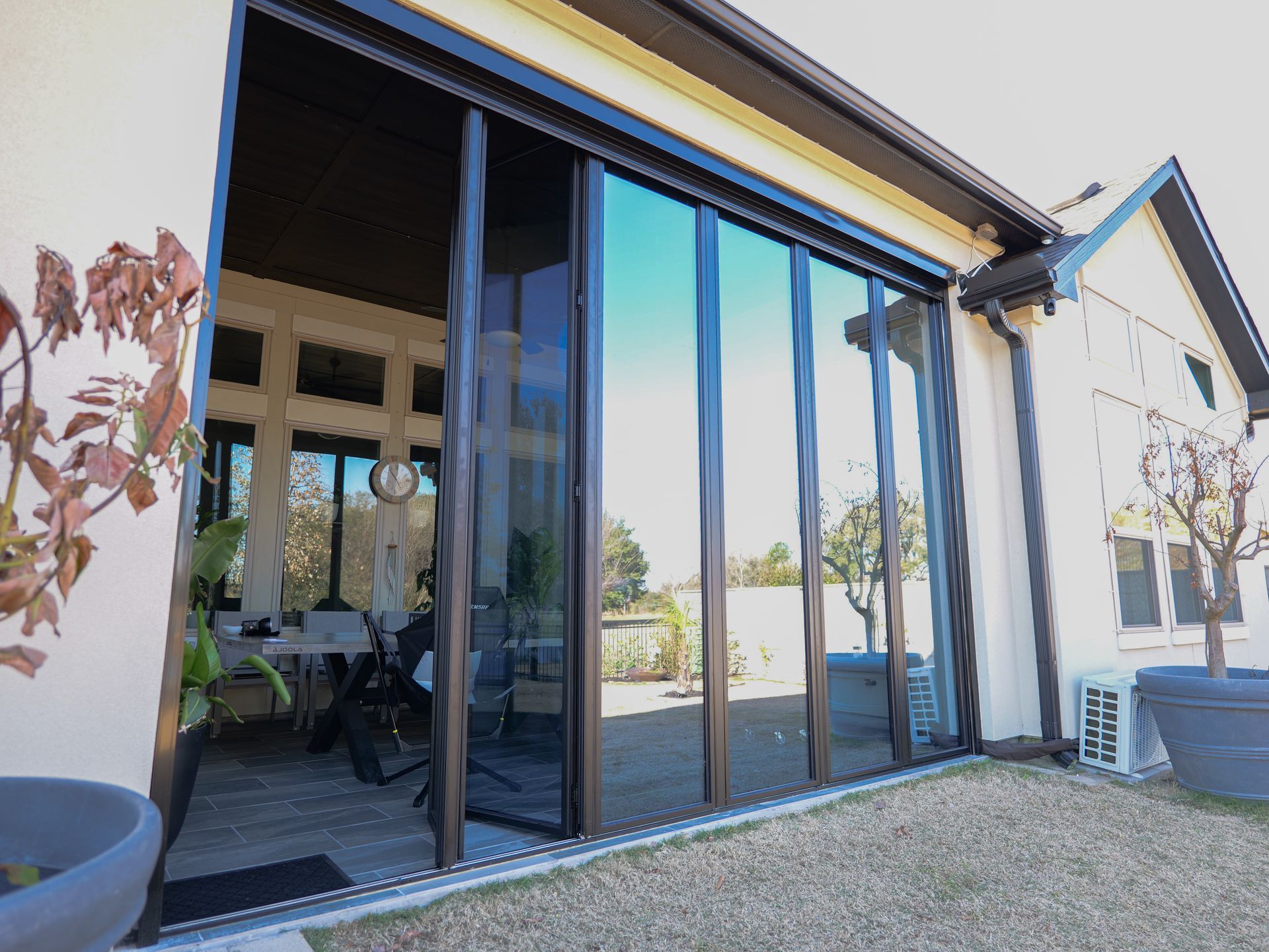 Modern glass folding doors opening to a patio and interior seating area