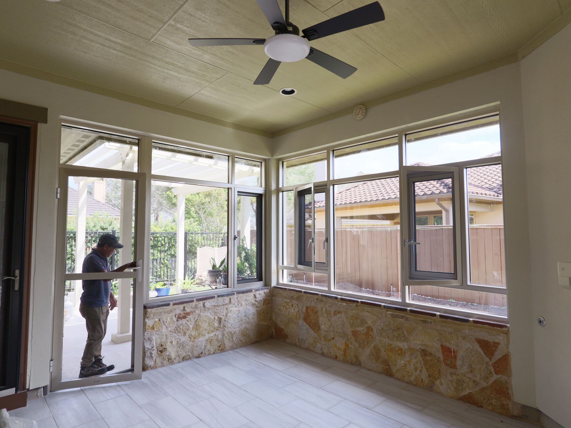 Enclosed porch with windows, ceiling fan, and a person standing by the door.