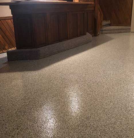 Shiny speckled floor in a wood-paneled room, with a dark wooden counter along the wall.