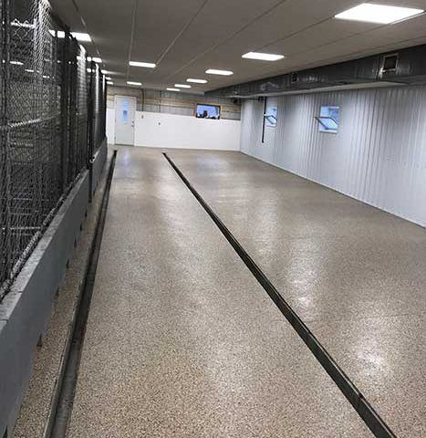 Empty indoor corridor with white walls, gray floor, and overhead fluorescent lights