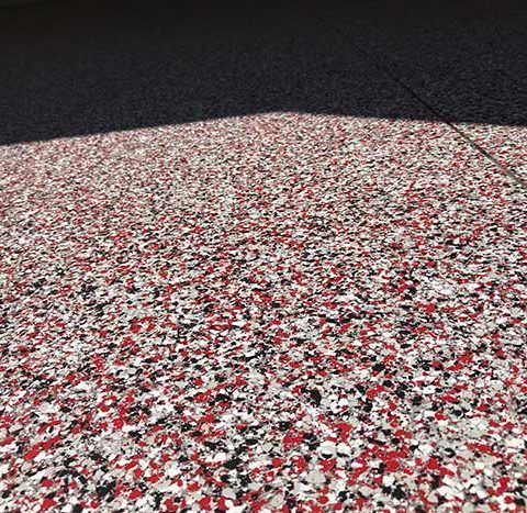 Red, white, and black speckled textured surface in bright light with a dark shadow across the top