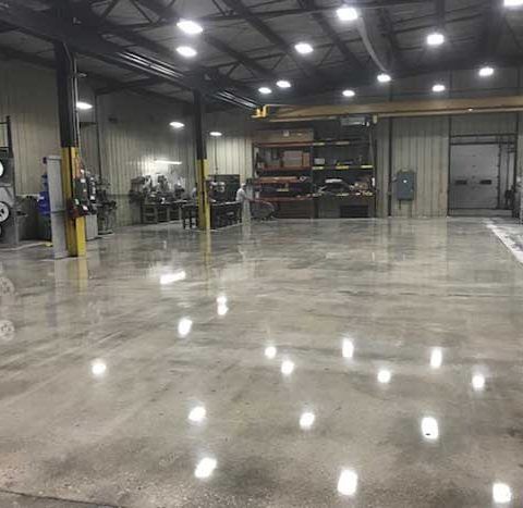Empty industrial warehouse with glossy concrete floor and overhead lights