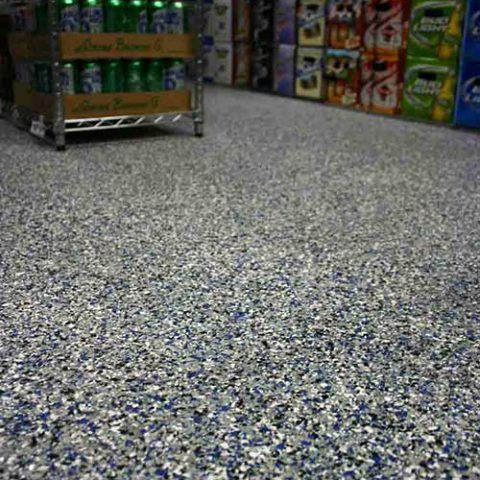 Grocery store aisle with patterned speckled floor, snack shelves along the sides, and a pallet of drinks on the left
