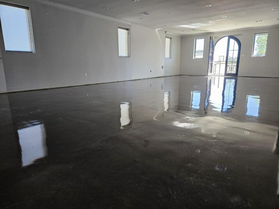 Empty white hall with a glossy black floor reflecting windows and an arched doorway.