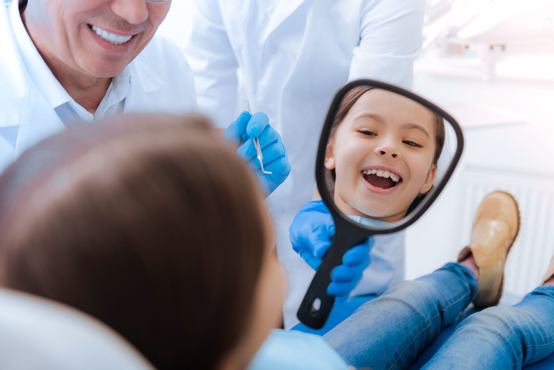 A joyful girl looking into the mirror and smiling while being in the dentist's office A joyful girl looking into the mirror and smiling while being in the dentist's office