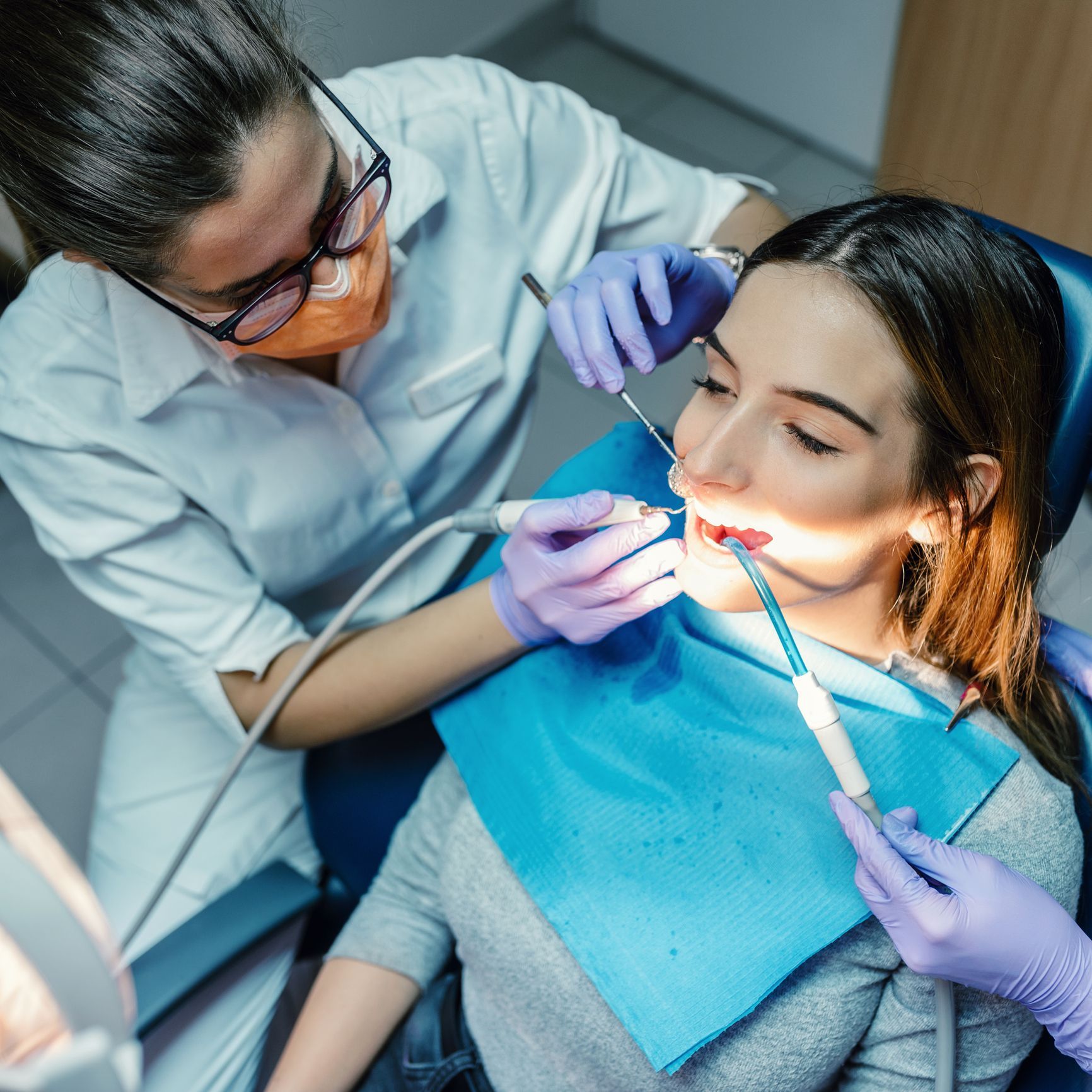 A female dentist is examining a young patient's teeth using dental tools in a clinic.