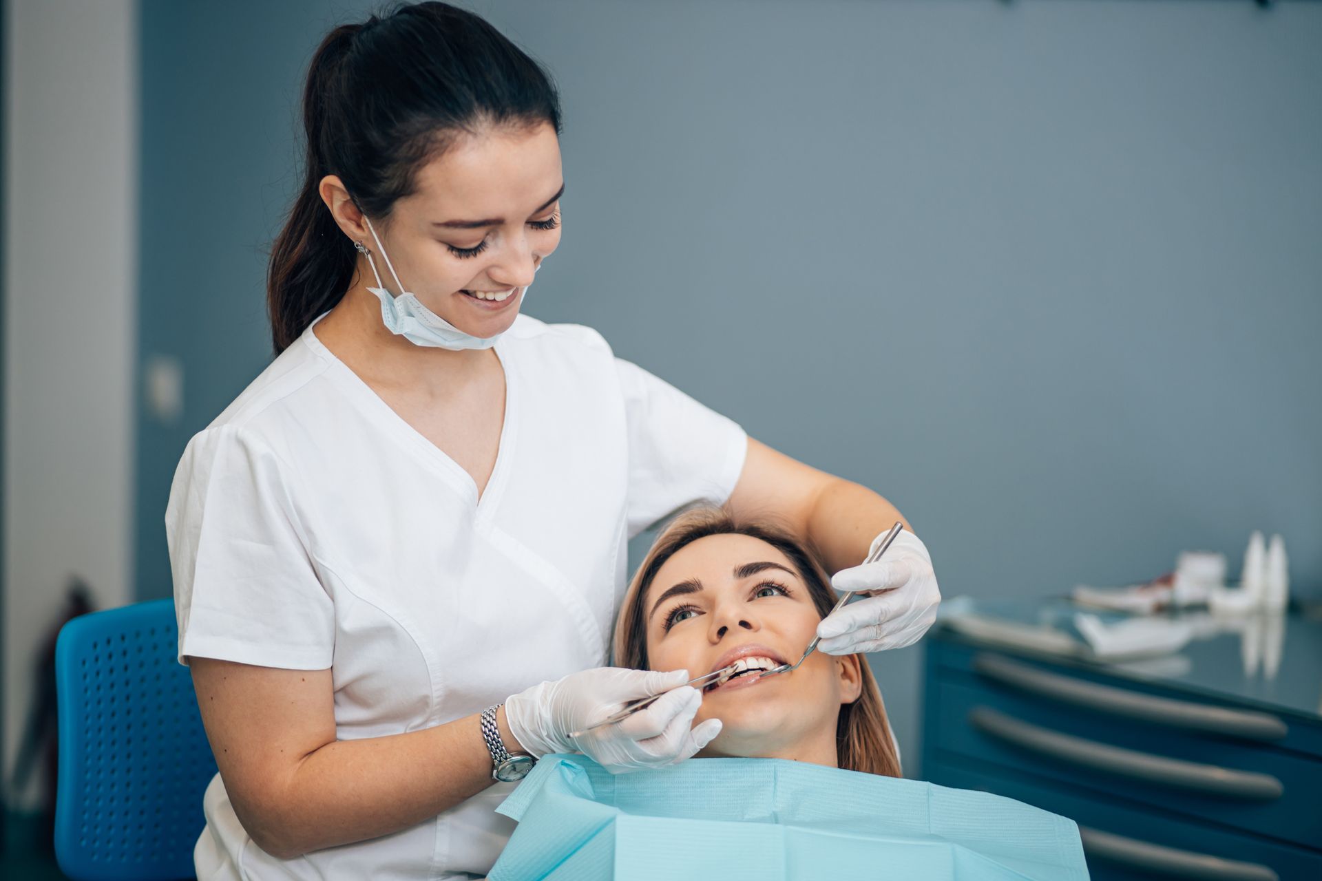 A female dentist is examining a woman 's teeth in a dental office.