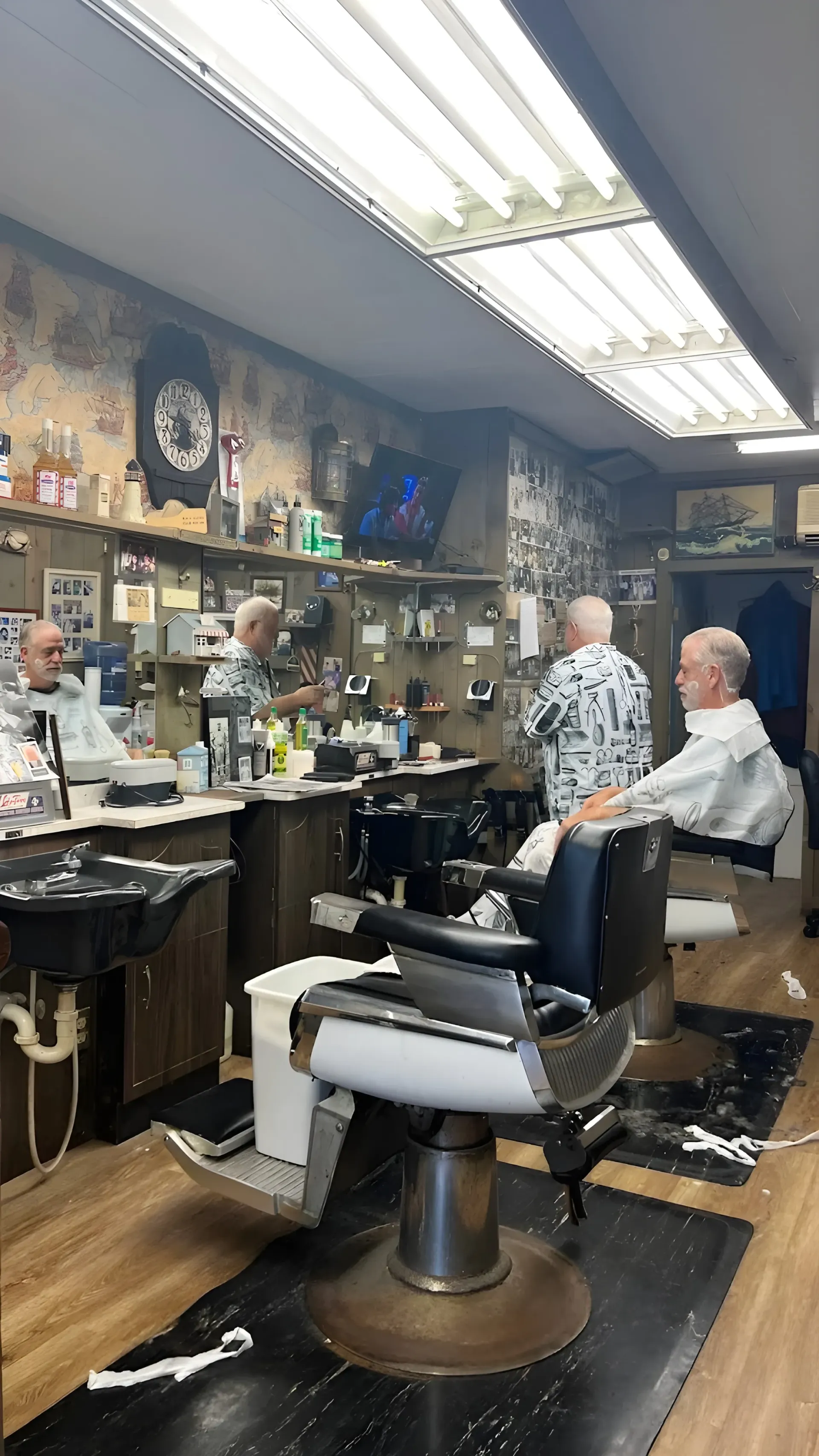Hair salon interior with barber chairs, mirrors, products, and two customers seated in the back.