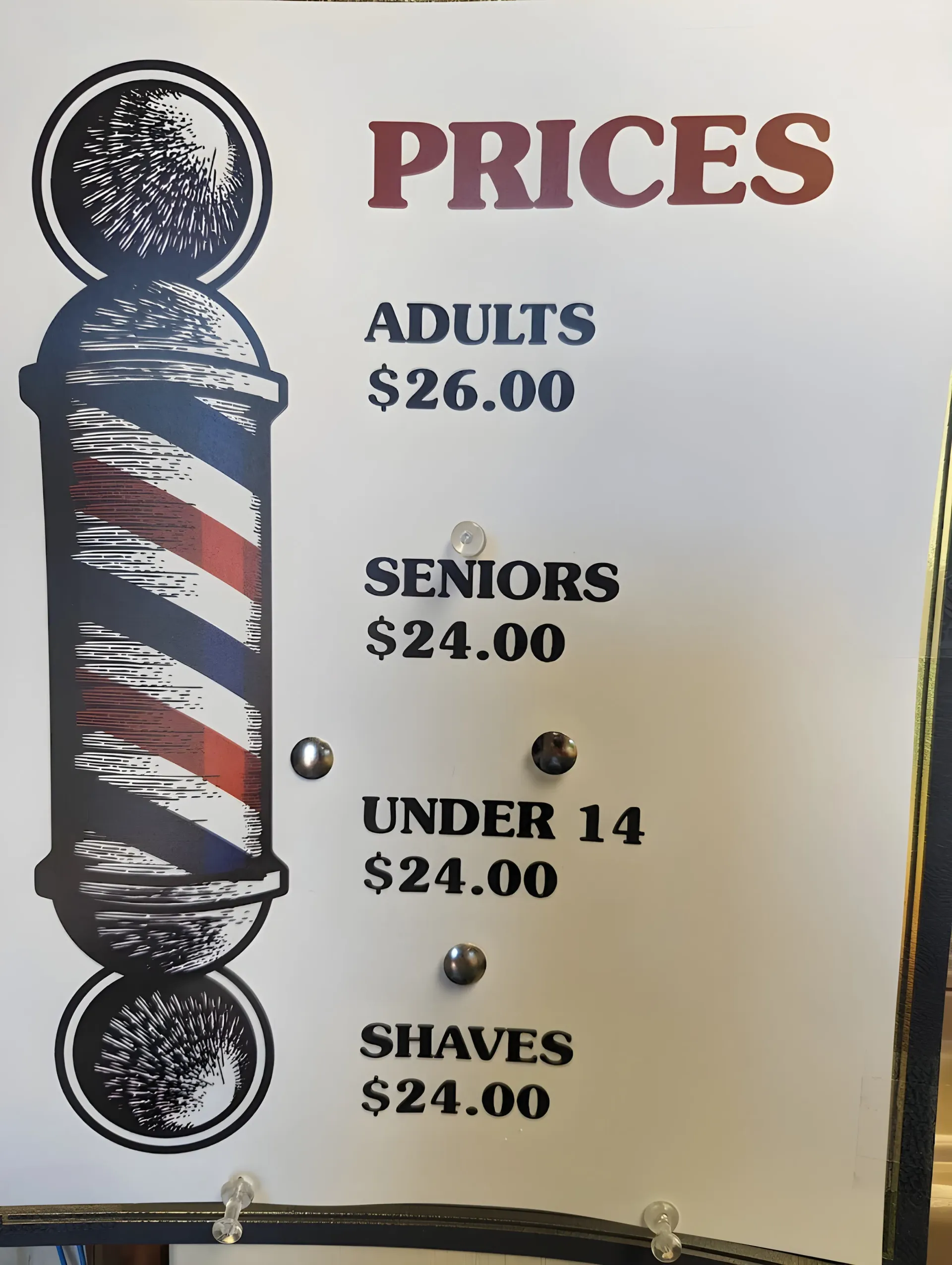 Barbershop price sign with red “PRICES” header and listed haircut rates for adults, seniors, under 14, and shaves
