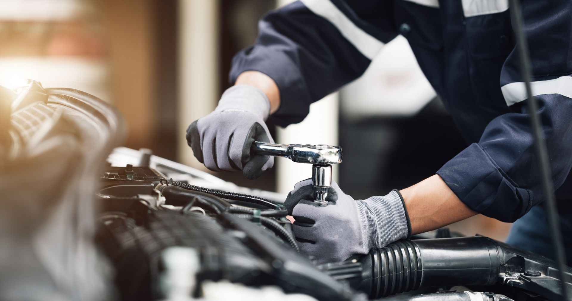 A mechanic is working on a car engine in a garage.