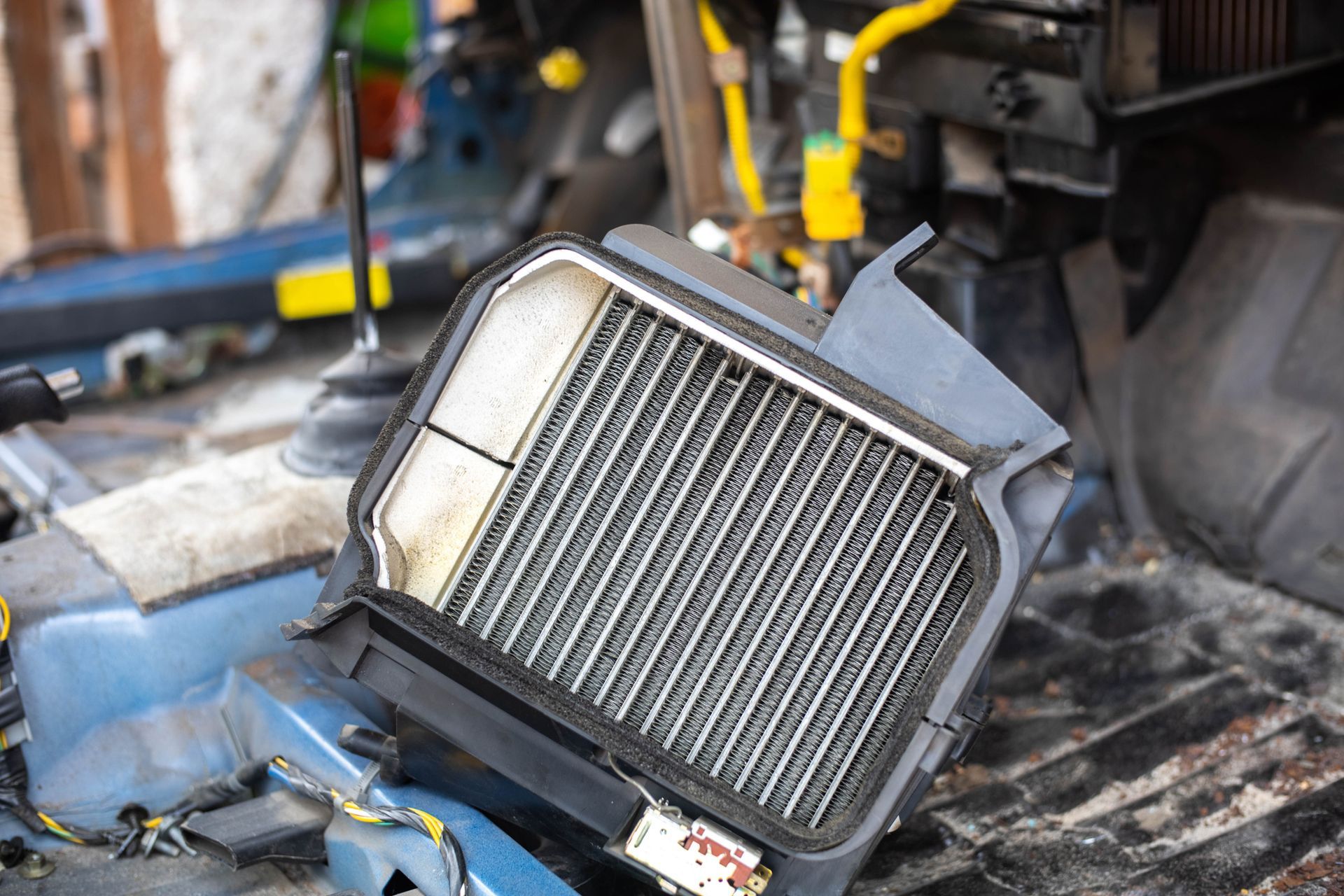 A person is holding a radiator in front of a car.