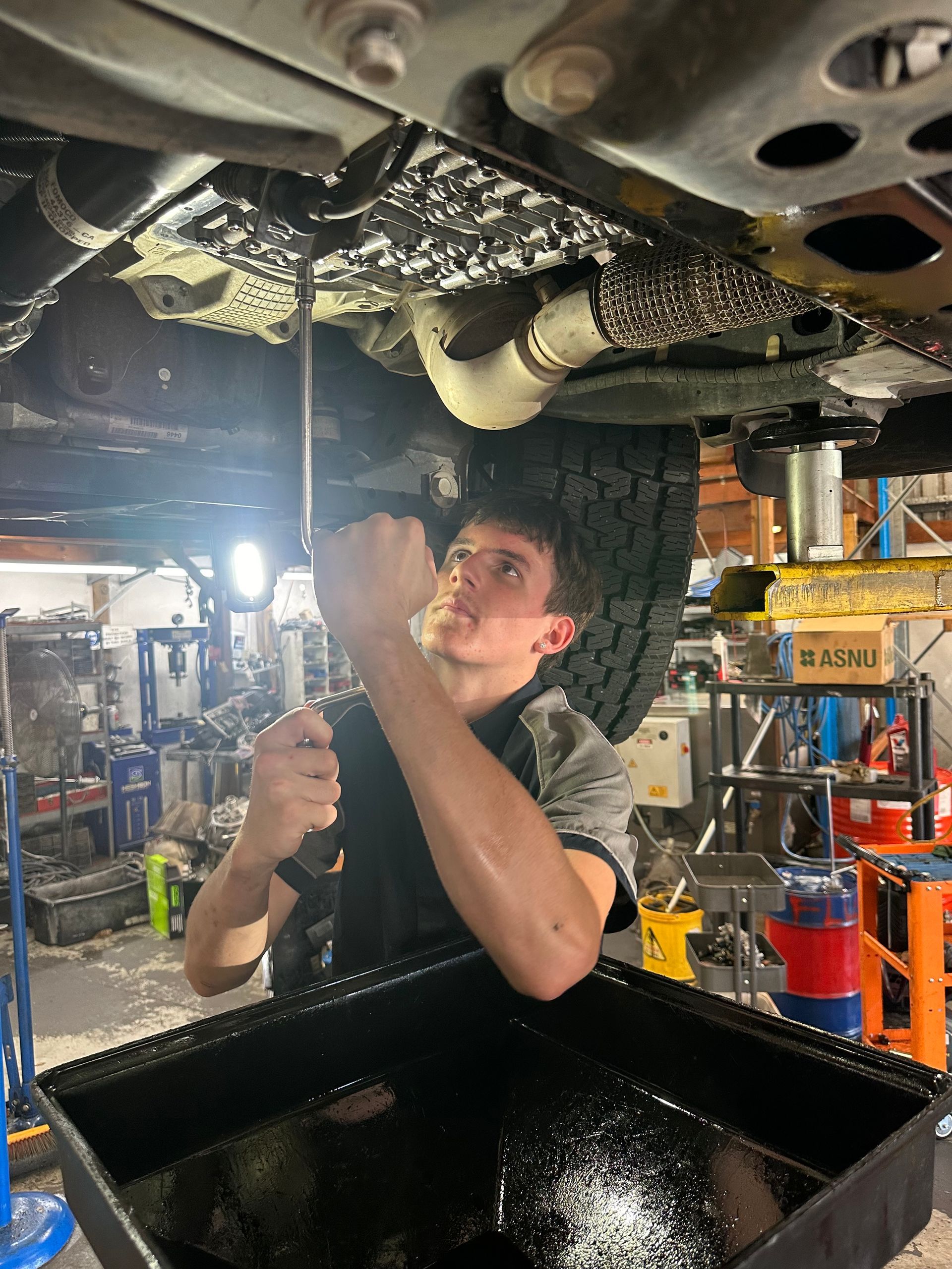 A man is pouring oil into a car through a funnel.