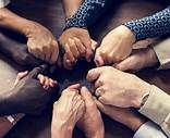 Several hands joined together in a circle on a wooden surface, symbolizing teamwork and unity