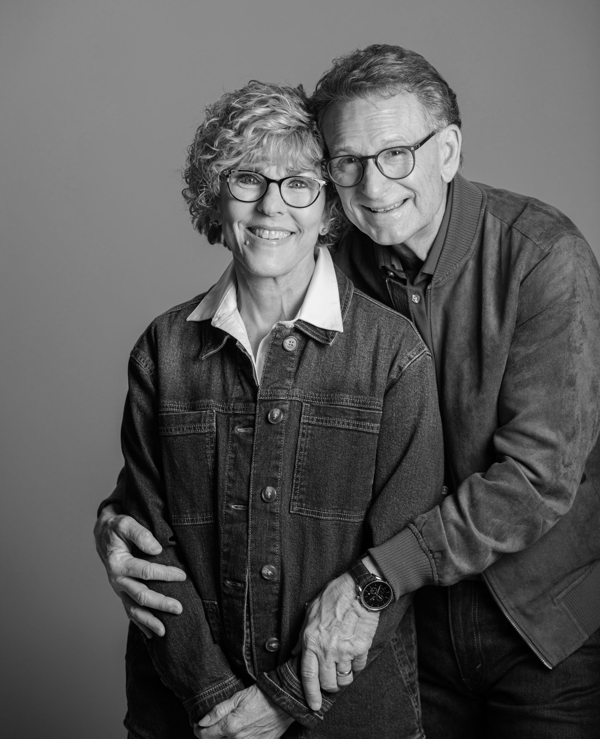 Two people smiling and embracing in a black-and-white portrait