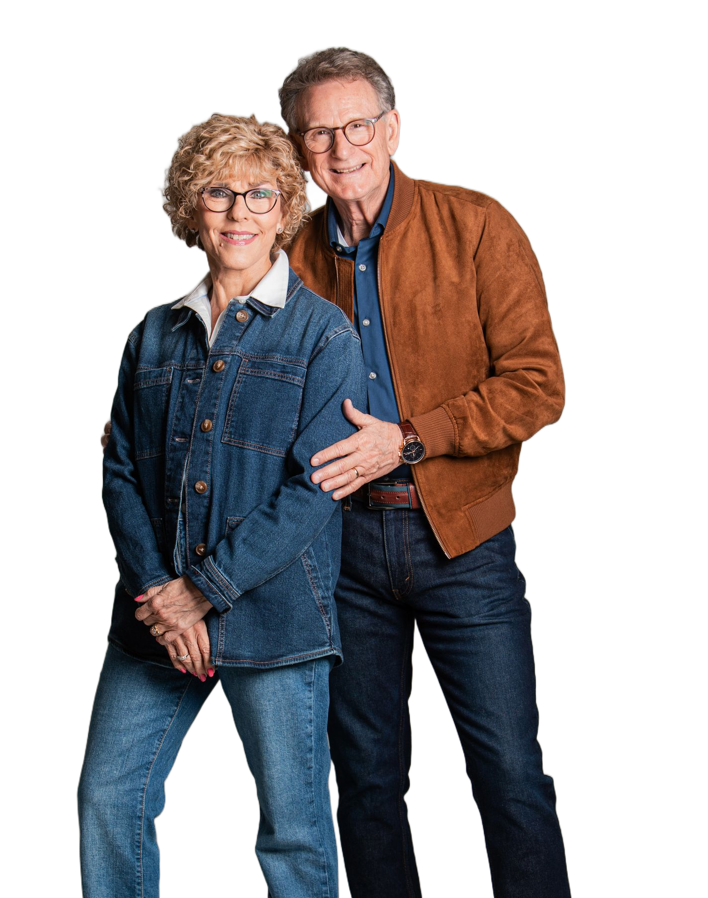 Two people standing together, wearing denim and brown jackets, posing against a white background.