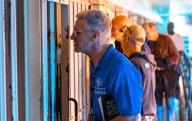 People in blue shirts lean into viewing windows along a brightly lit corridor.