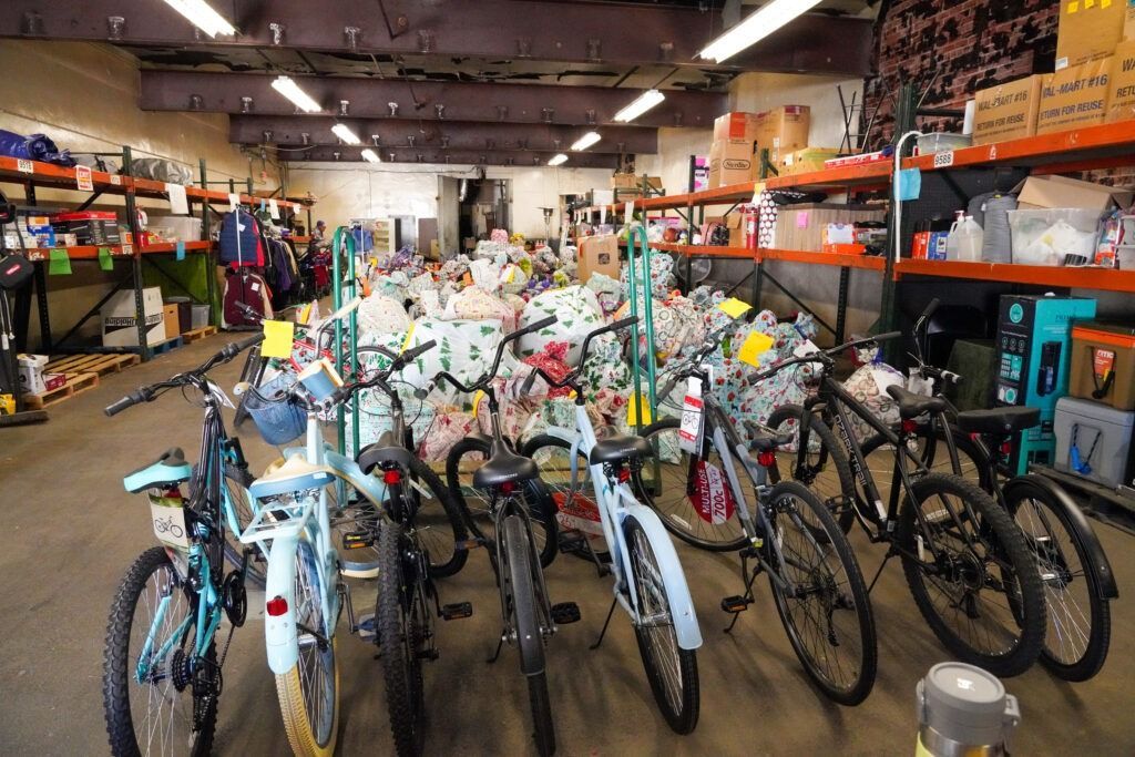 Bikes for sale inside a cluttered bicycle shop, with rows of colorful bikes and gear on shelves.