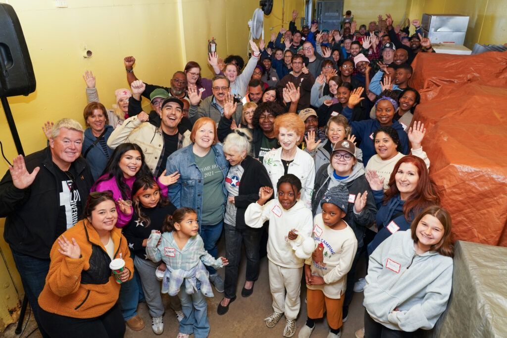 Large group gathered indoors on a staircase, smiling and posing for a group photo.
