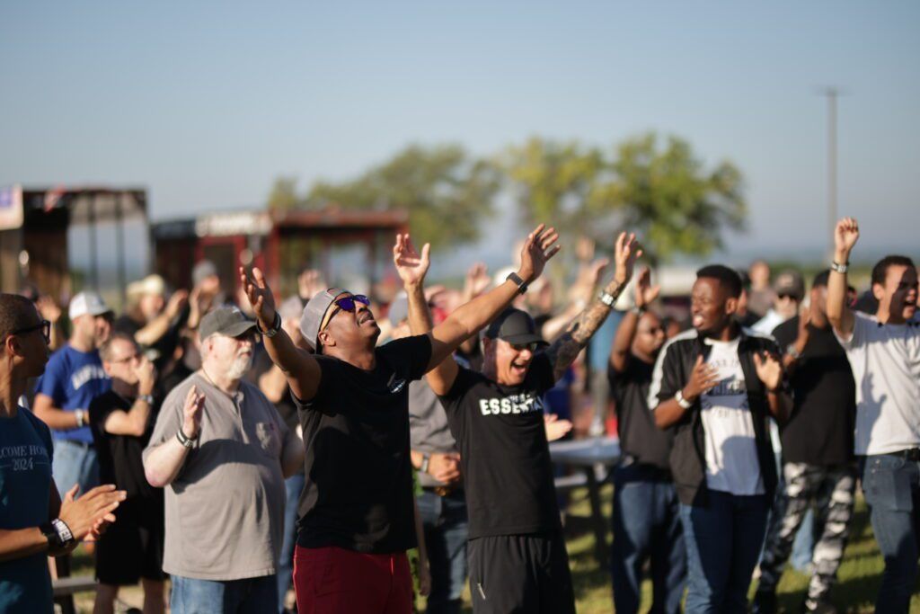 Crowd outdoors cheering with hands raised in sunlight