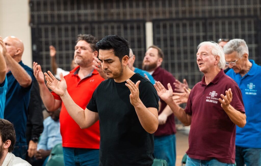 People standing indoors with hands raised in a group activity or prayer session
