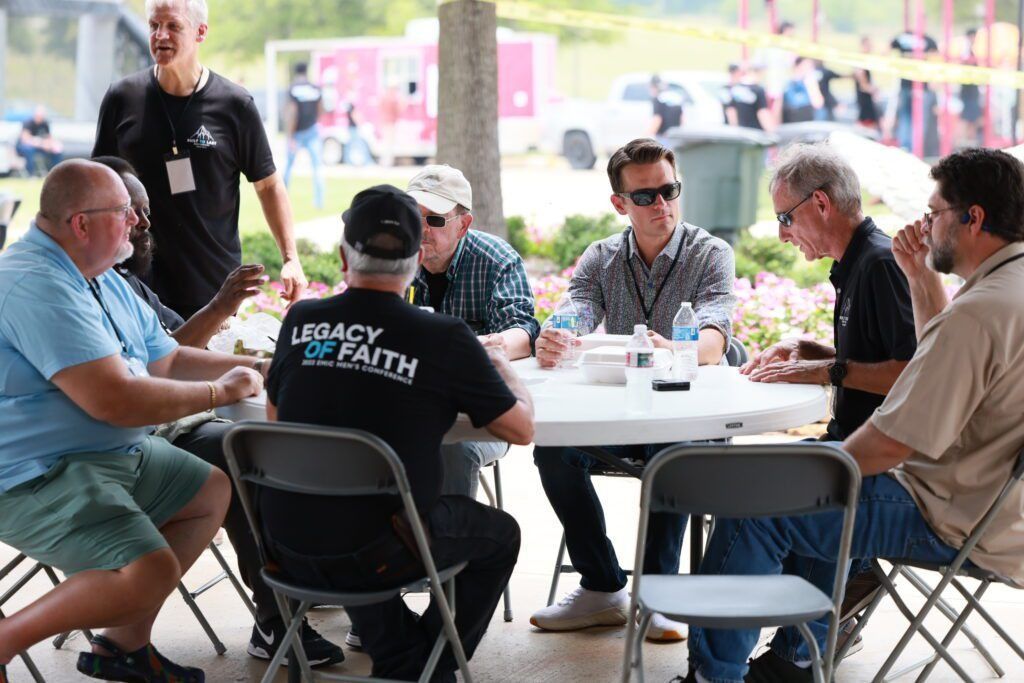 People seated around a table chatting outdoors at a covered patio event