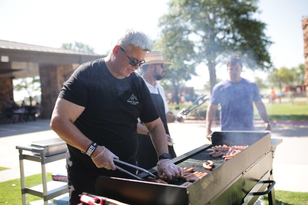 Man grilling skewers outdoors at a sunny park barbecue