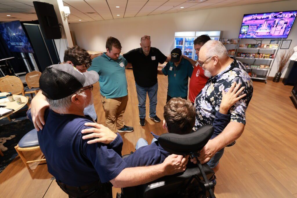 Group of people standing in a circle around a seated person in a bright indoor room
