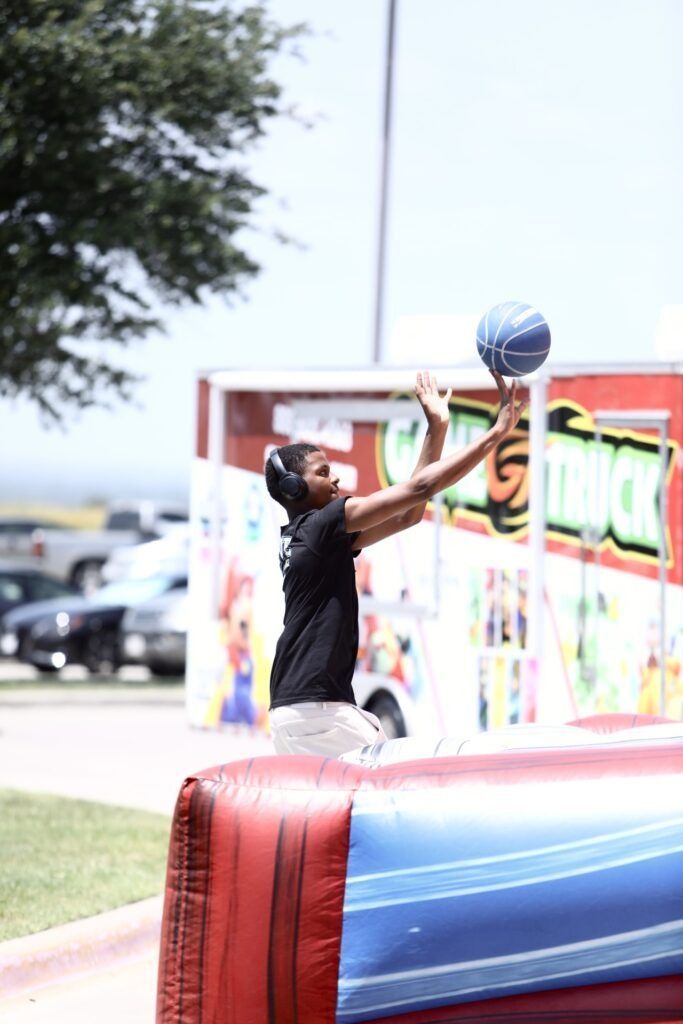 Person reaching for a blue basketball near a red inflatable court outdoors