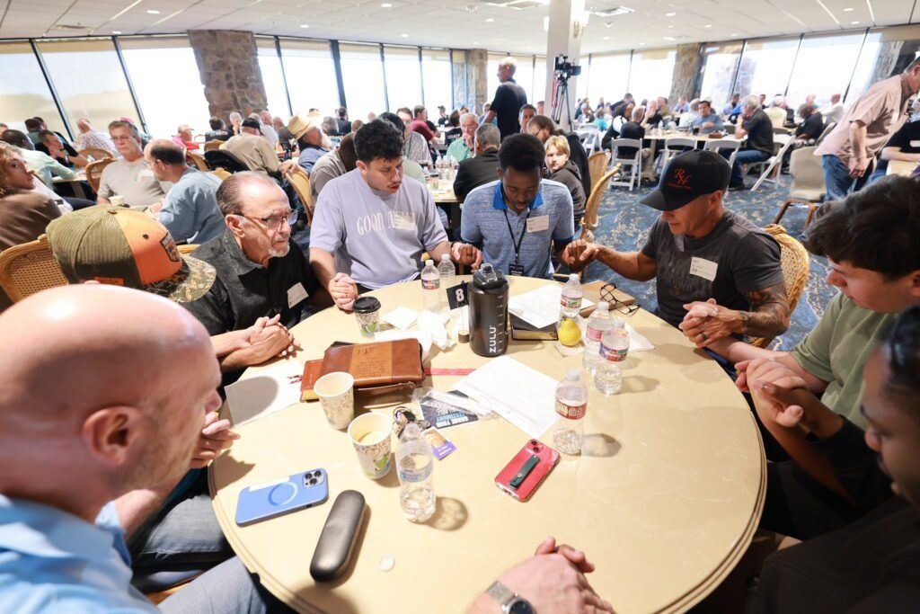 People gathered around a round table in a bright conference room, eating and talking.