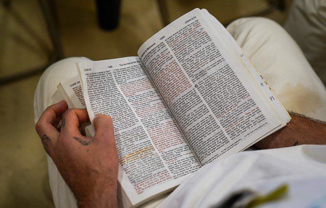 Person holding an open book and reading in a beige chair