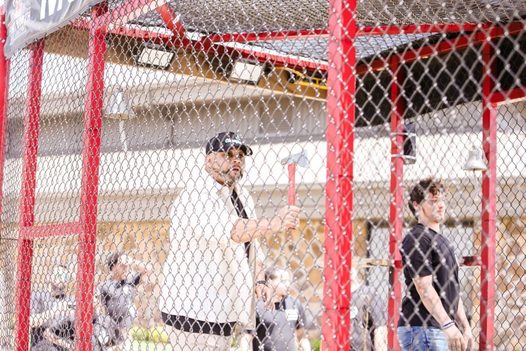 People behind a red chain-link fence at an indoor sports court