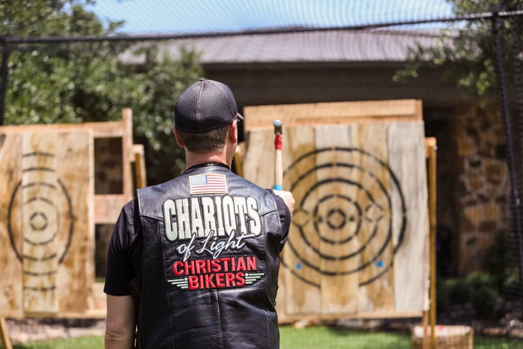Person stands before two wooden target boards at an outdoor axe-throwing range.