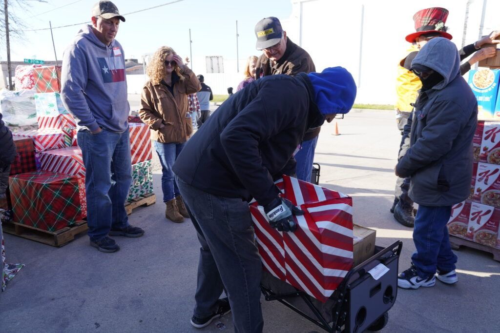 People loading an American flag-covered wagon at an outdoor event on a cold day