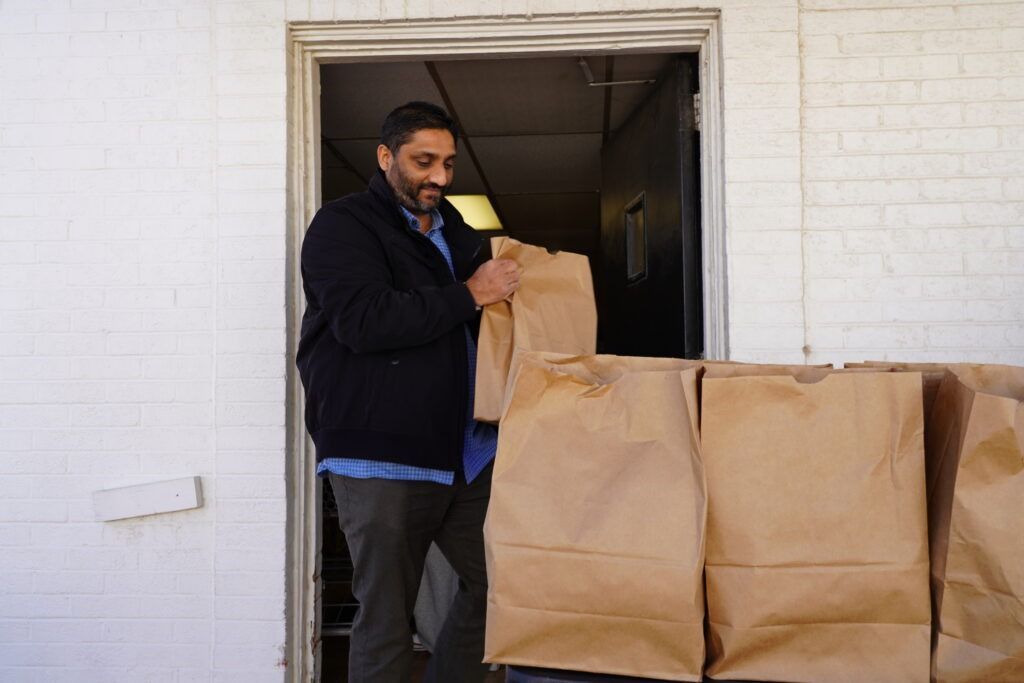 Man loading large brown paper bags at a doorway